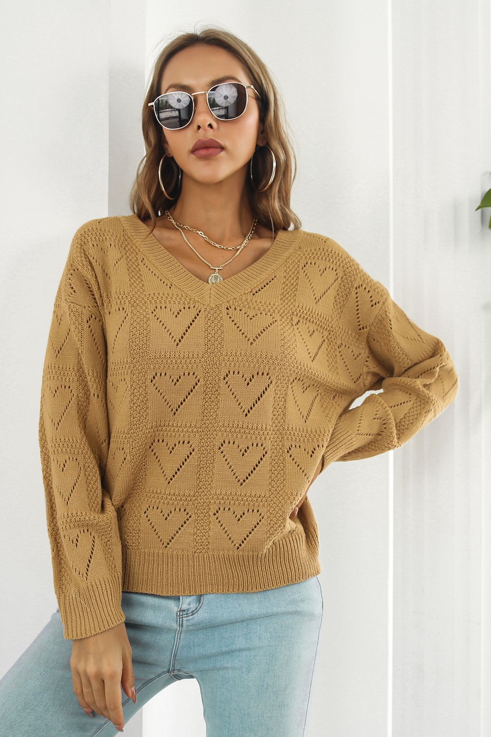Camel V-neck knit pullover sweater with allover heart stitch pattern and ribbed cuffs and hem.