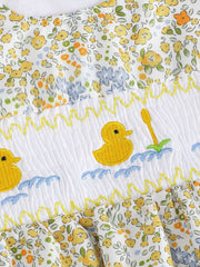 Baby one-piece with floral print, smocked white panel, and embroidered yellow ducks in water.