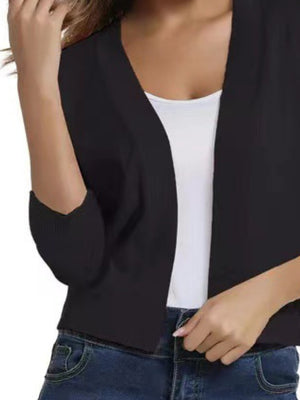 Black open-front cropped cardigan with elbow sleeves, worn over a white tank top.