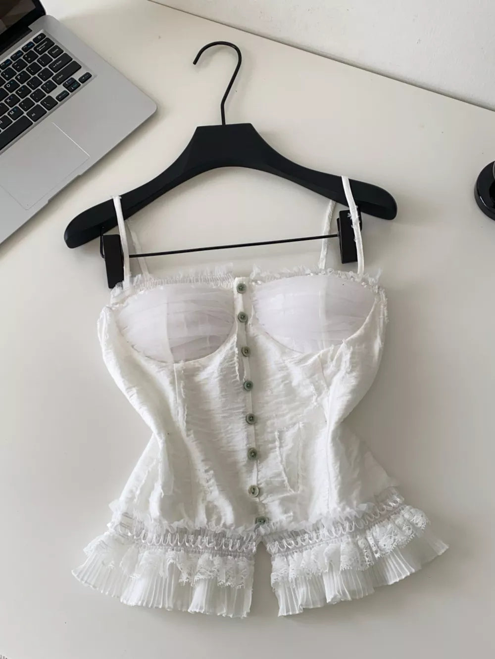 White lace ruffle hem tank top with button front and sheer bust detail.