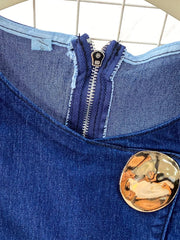 Dark blue cotton denim vest with asymmetrical zipper and large gold button detail.
