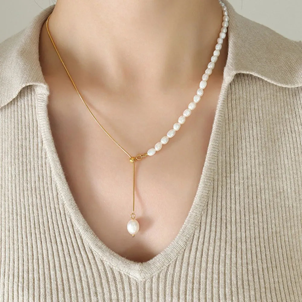 Gold asymmetrical lariat necklace with pearls and a single pearl drop pendant.