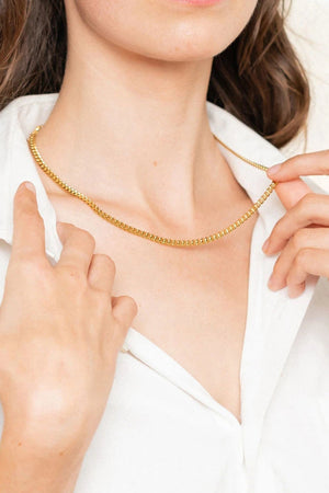 Sculpted gold chain necklace with 18K gold plating, worn as a choker.