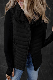 Black quilted puffer vest with soft fleece collar and zip front, worn over a long sleeve top.