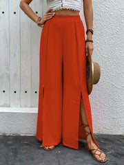 Orange-red textured palazzo trousers with dramatic thigh-high slits and wide legs.