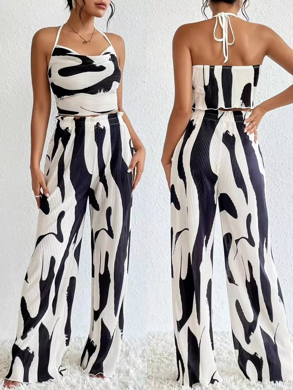 Chic abstract print crop top and pants set in black and white polyester with halter neck and wide leg pants.