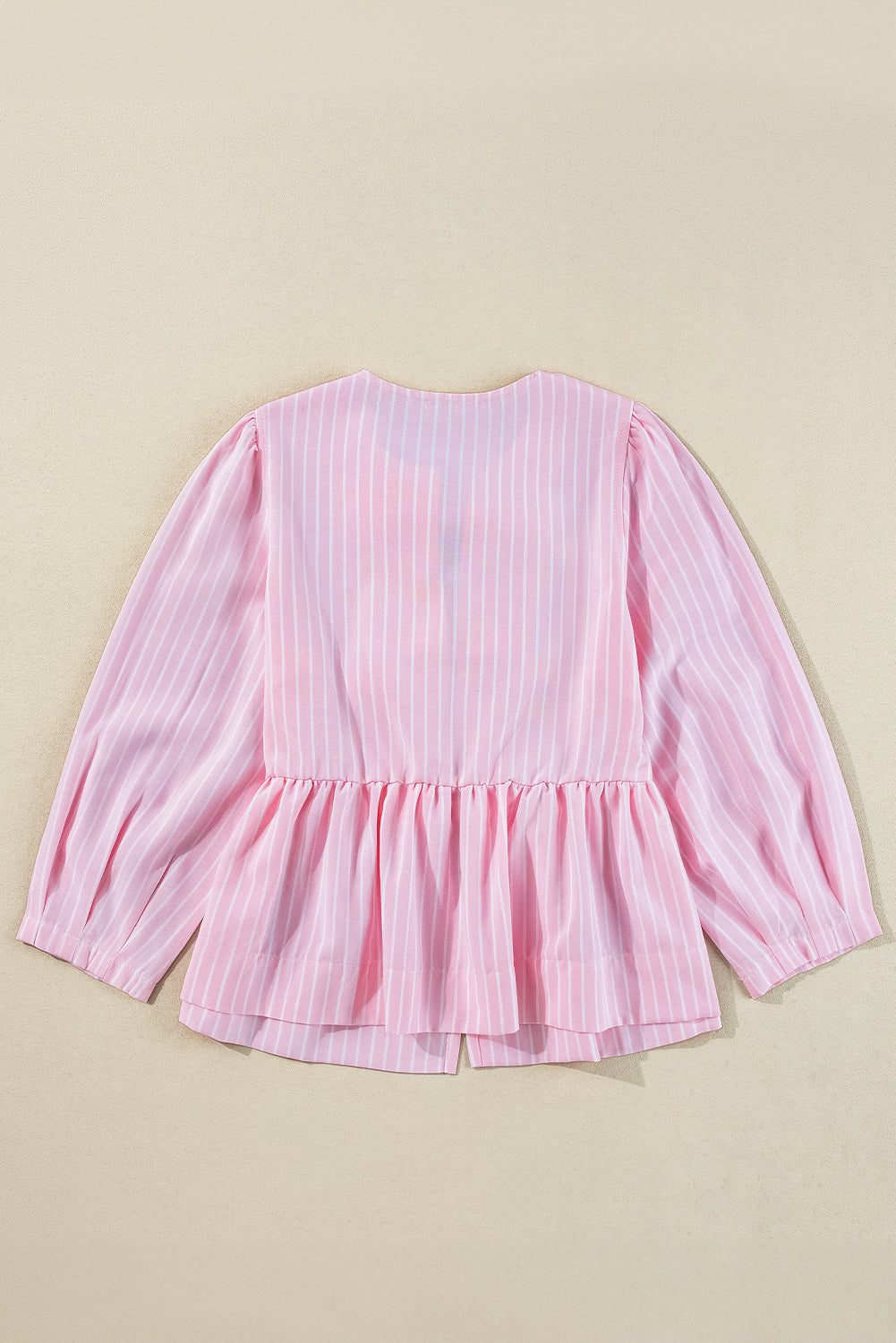 Blush pink striped peplum blouse with long puff sleeves and a ruffled hem.
