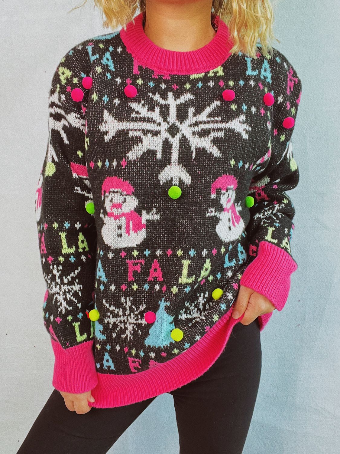 Black knit sweater with snowmen, snowflakes, and pom-pom details.
