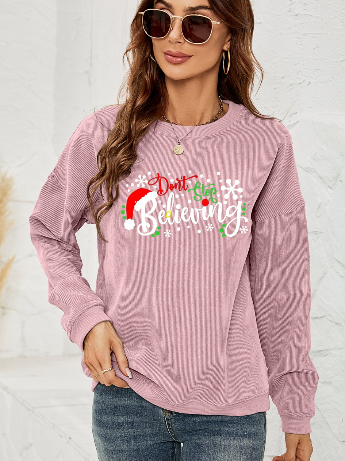 Dusty Pink corduroy crewneck sweatshirt with "Don't Stop Believing" Christmas graphic and snowflakes.