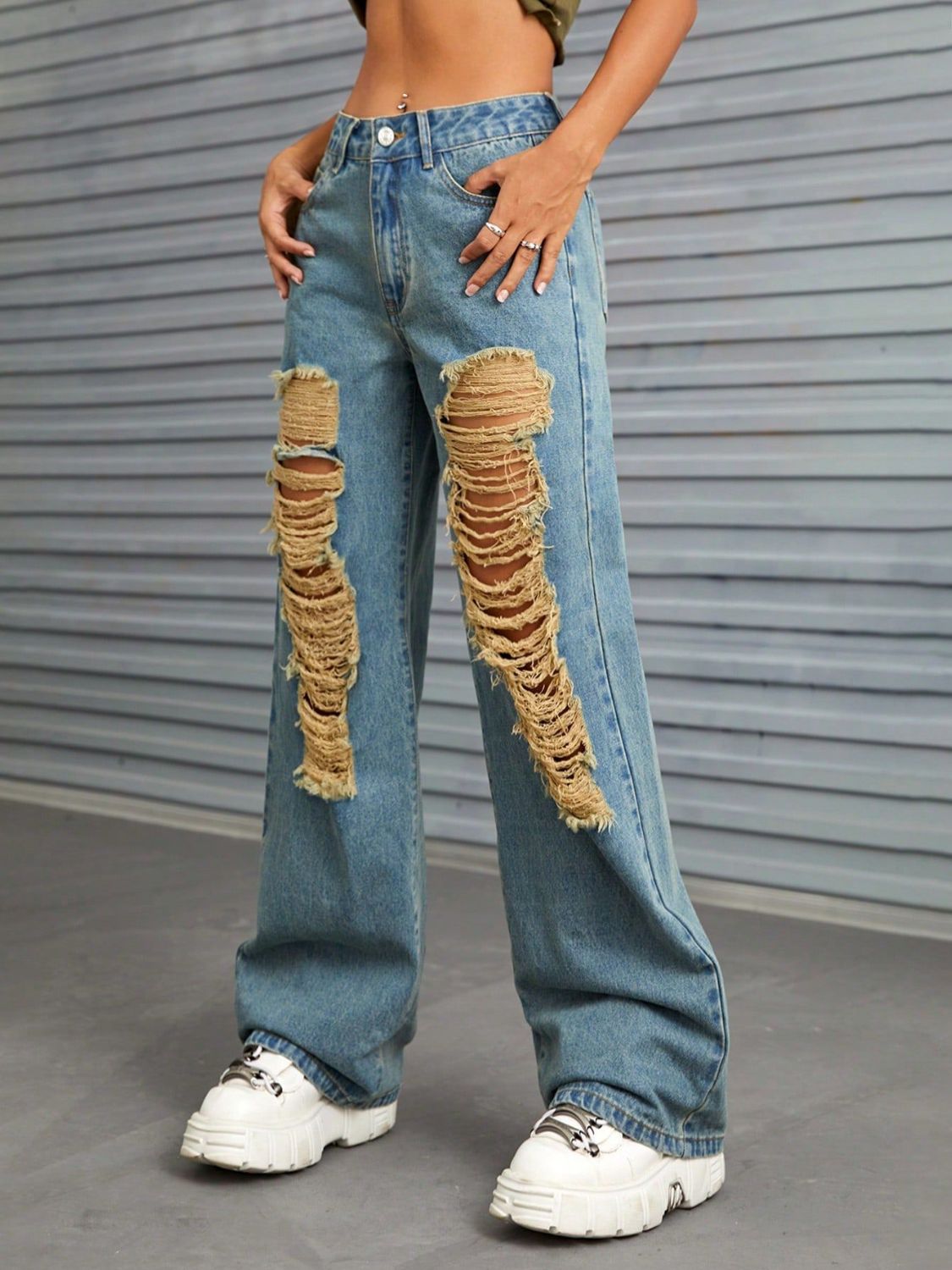 Medium wash denim jeans with large distressed rips and raw edge detail