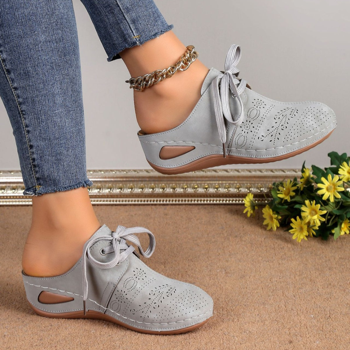 Light gray perforated slip-on mules with lace-up detail and open back.