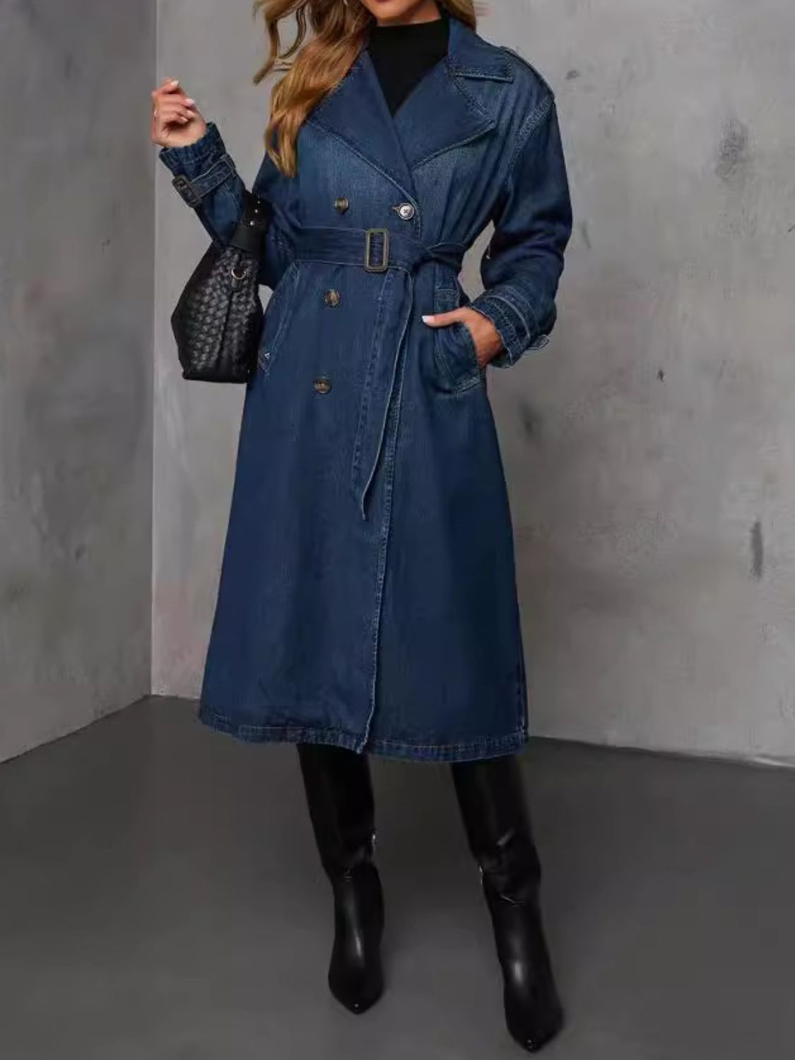 Denim trench coat in dark blue with belted waist, double-breasted buttons, and lapel collar.