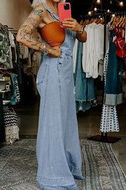Distressed light wash denim overalls with wide legs and button closure.