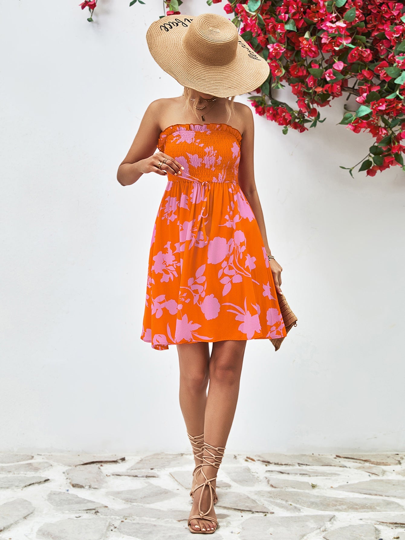Orange floral smocked bandeau mini dress with drawstring waist and ruffled hem.