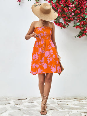 Orange floral smocked bandeau mini dress with drawstring waist and ruffled hem.