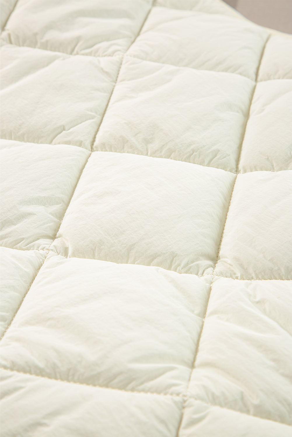 Ivory quilted stand collar vest detail showing diamond pattern stitching.