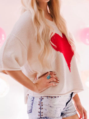 Beige V-neck knit sweater with red heart print, short sleeves, and a relaxed fit.