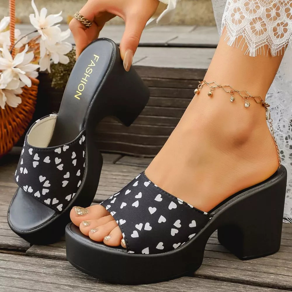 Black heart print block heel sandals with platform sole and open toe.