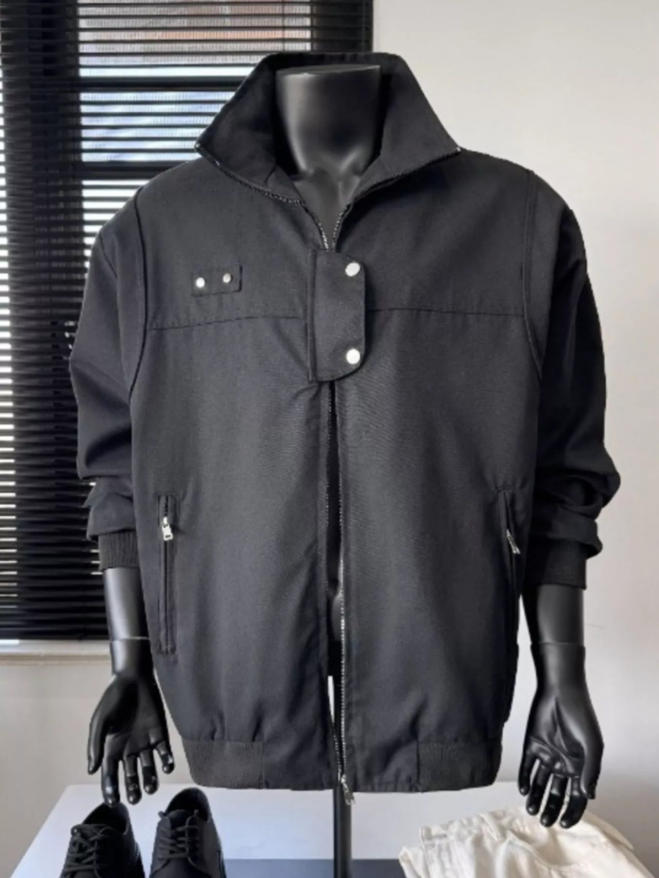 Black casual bomber jacket with zip front, stand collar, and buttoned flap details.