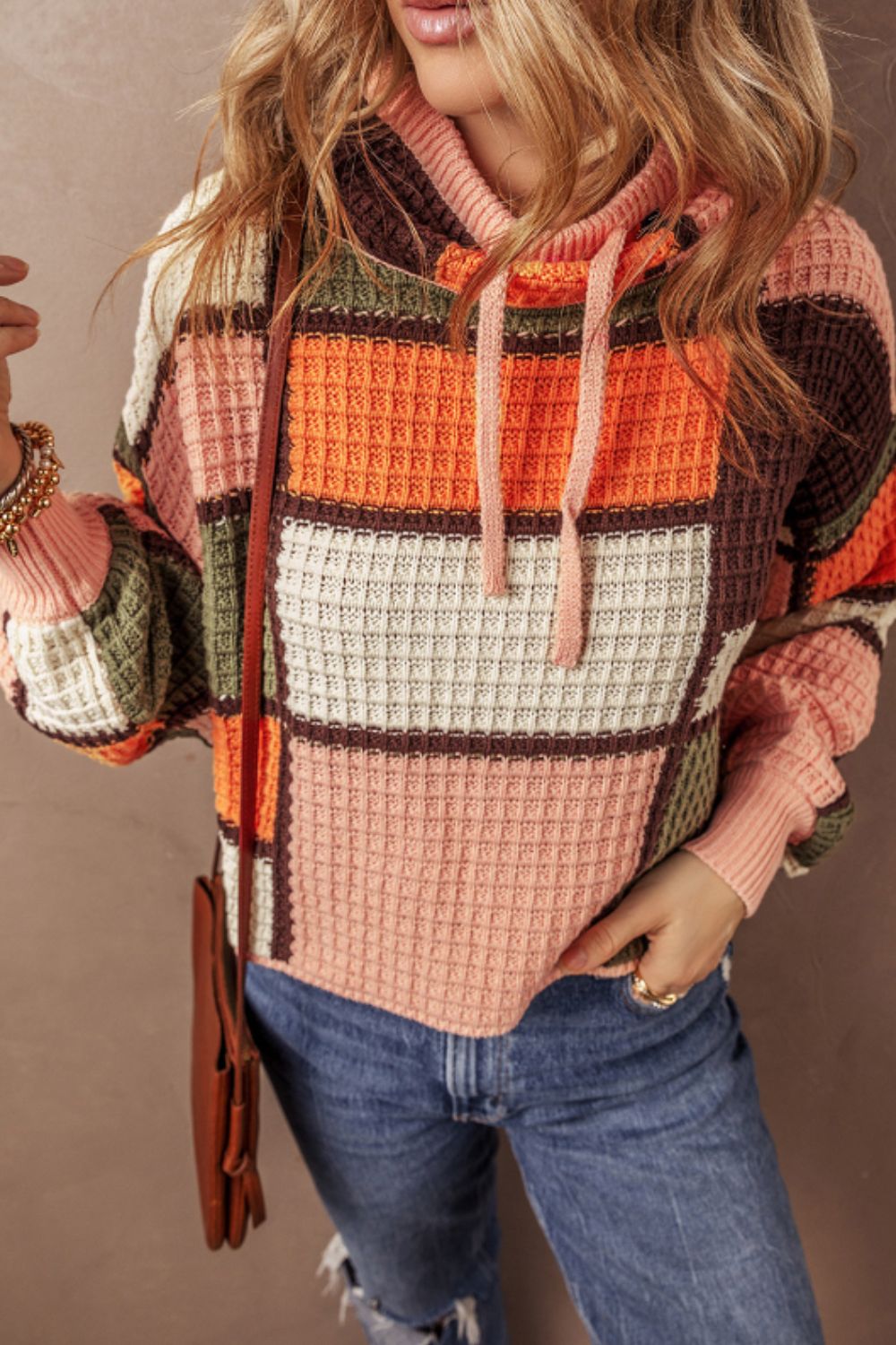 Waffle knit patchwork hoodie in orange, pink, green, cream, and brown with drawstring hood and ribbed cuffs.