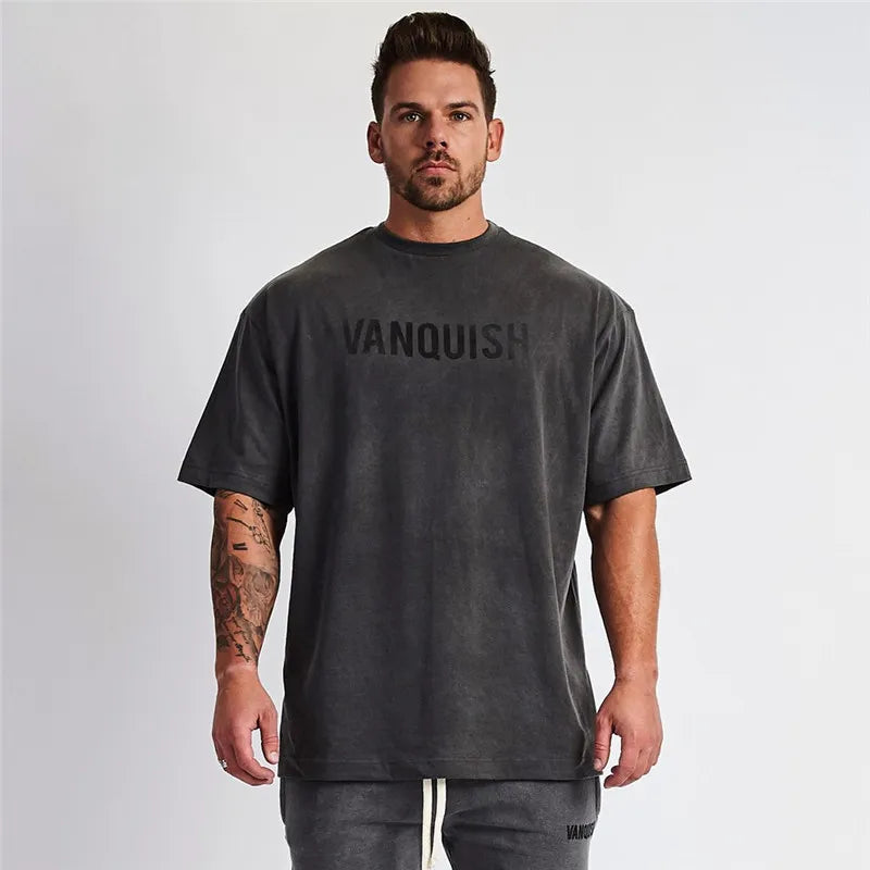Oversized dark gray graphic tee with black VANQUISH text, crewneck, and short sleeves.