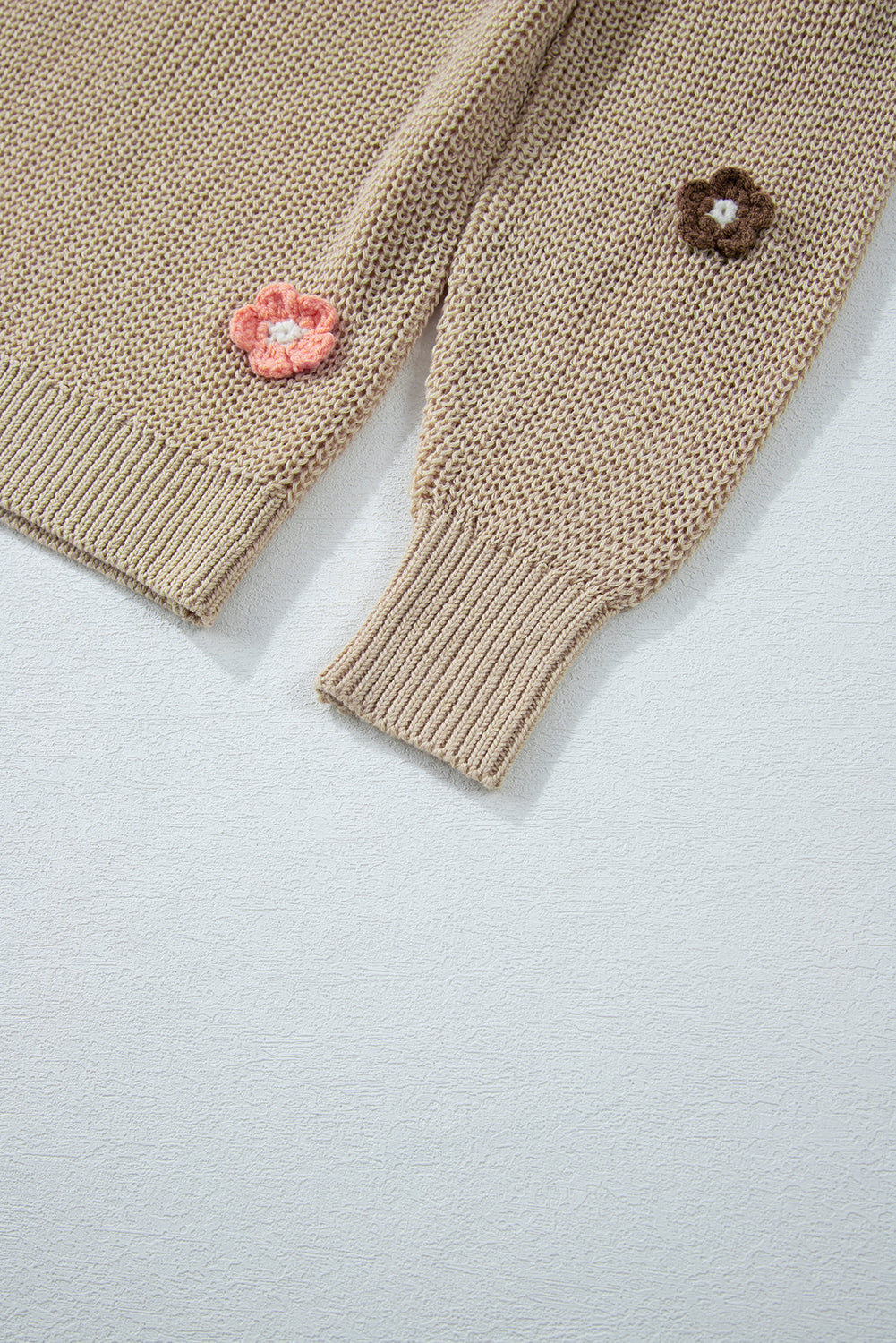 Khaki knit sweater with embroidered floral details on the sleeves and hem.