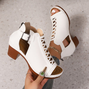 White criss-cross cut-out block heel sandals with ankle strap and chain detail.