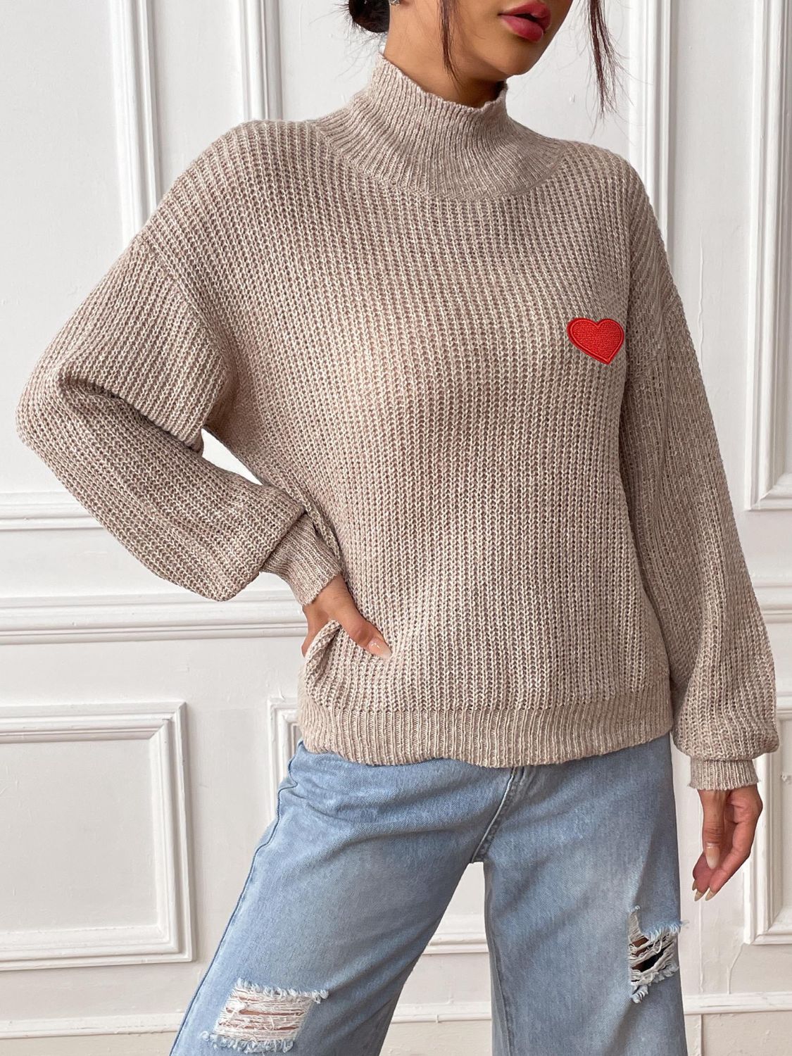 Khaki mock neck knit sweater with red heart appliqué and ribbed texture.