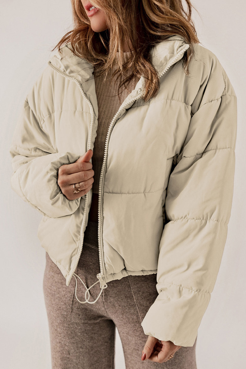 Cream cropped puffer jacket with hood, full zip, and drawstring hem.
