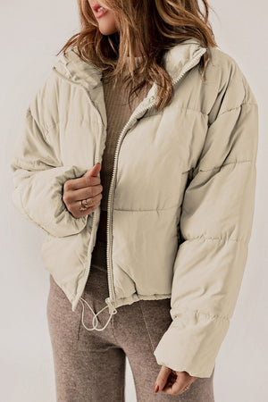 Cream cropped puffer jacket with hood, full zip, and drawstring hem.