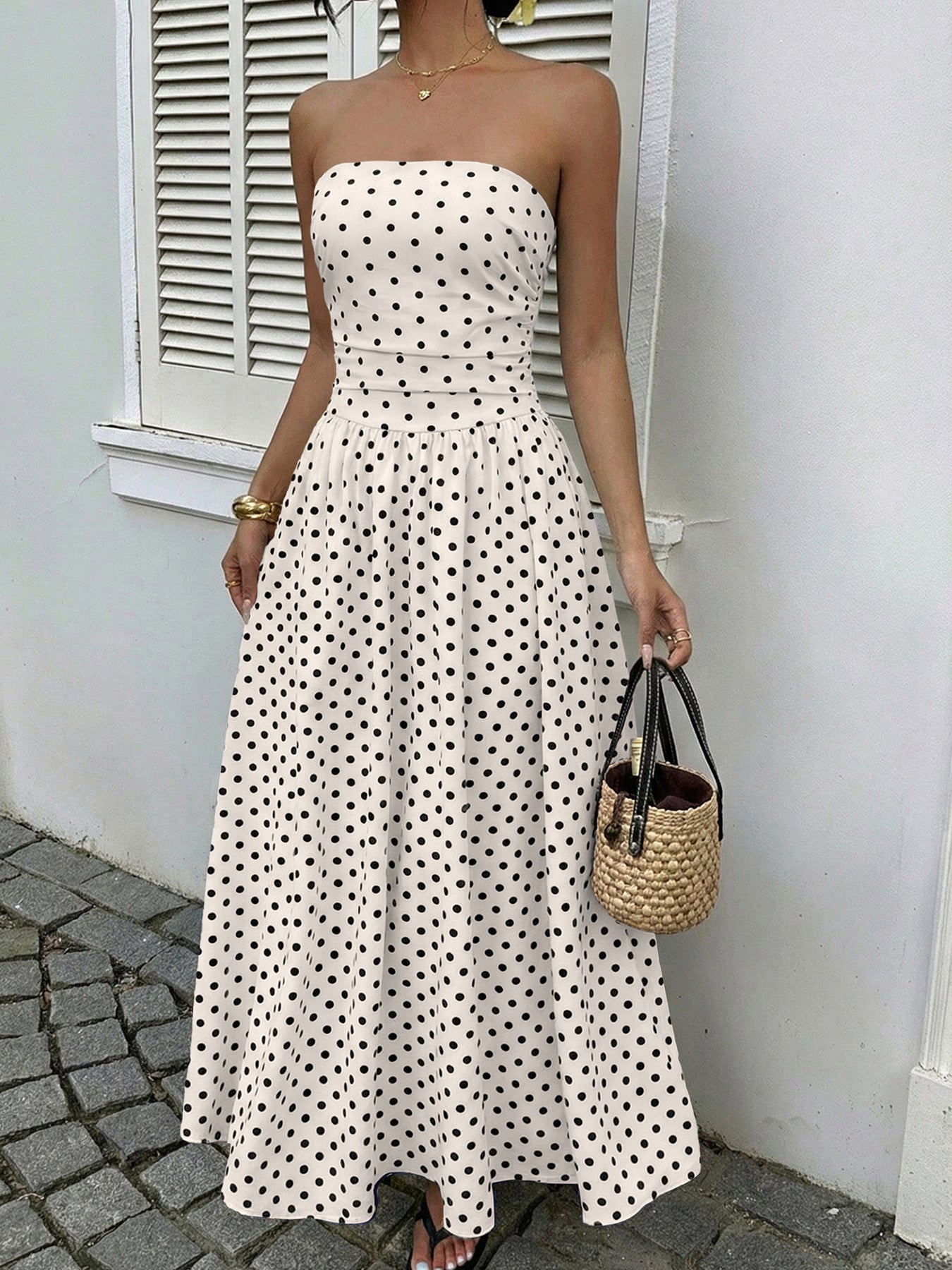White polka dot strapless maxi dress with a belted waist and A-line skirt.