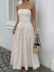White polka dot strapless maxi dress with a belted waist and A-line skirt.