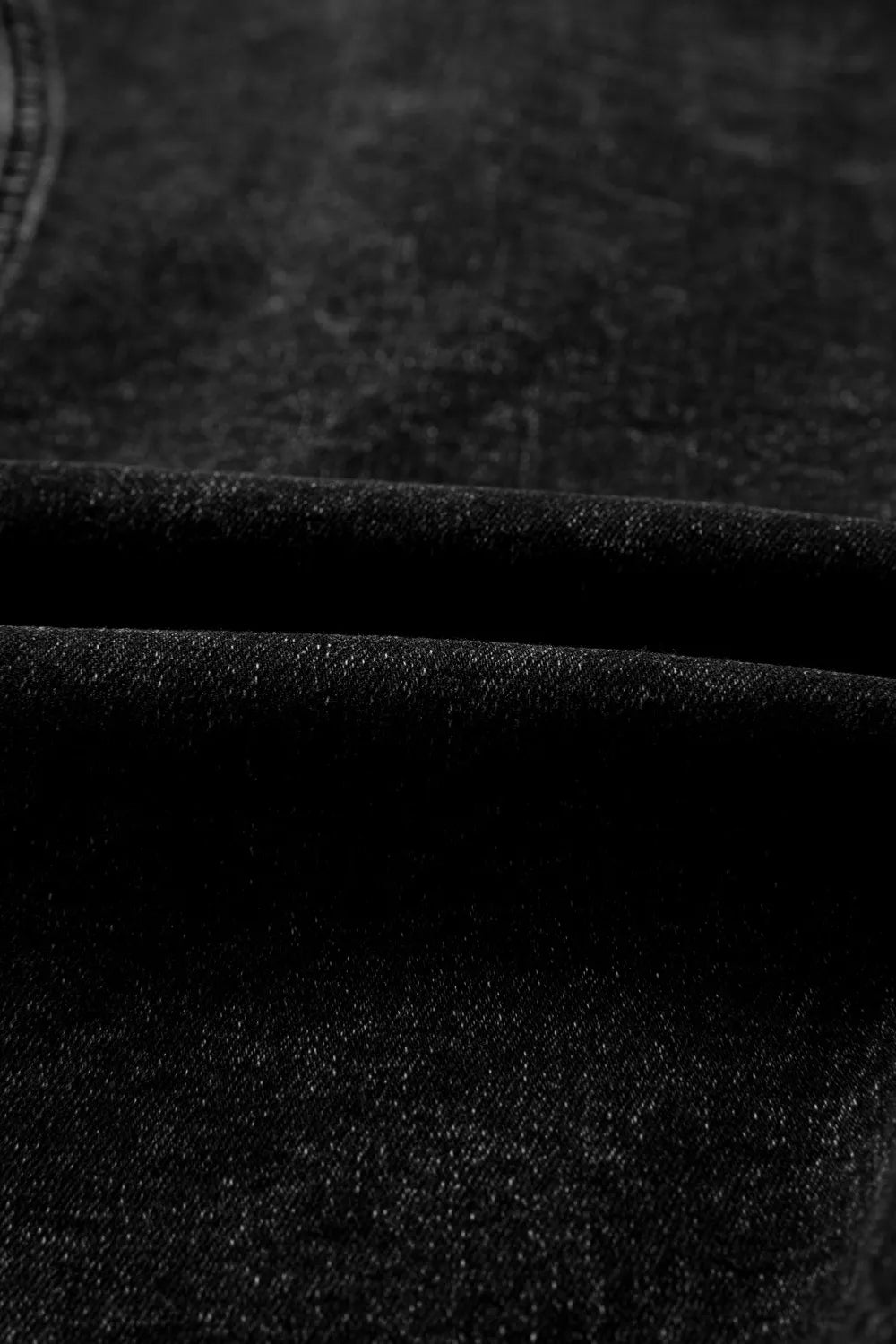 Black cotton denim vest with vintage wash texture, showing fabric detail.
