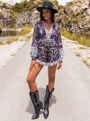 Floral print blouson sleeve romper with button front and ruffled hem, styled with cowboy boots.