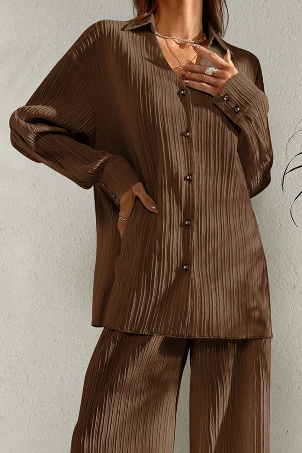 Brown pleated co-ord set with button-down shirt and wide leg trousers.