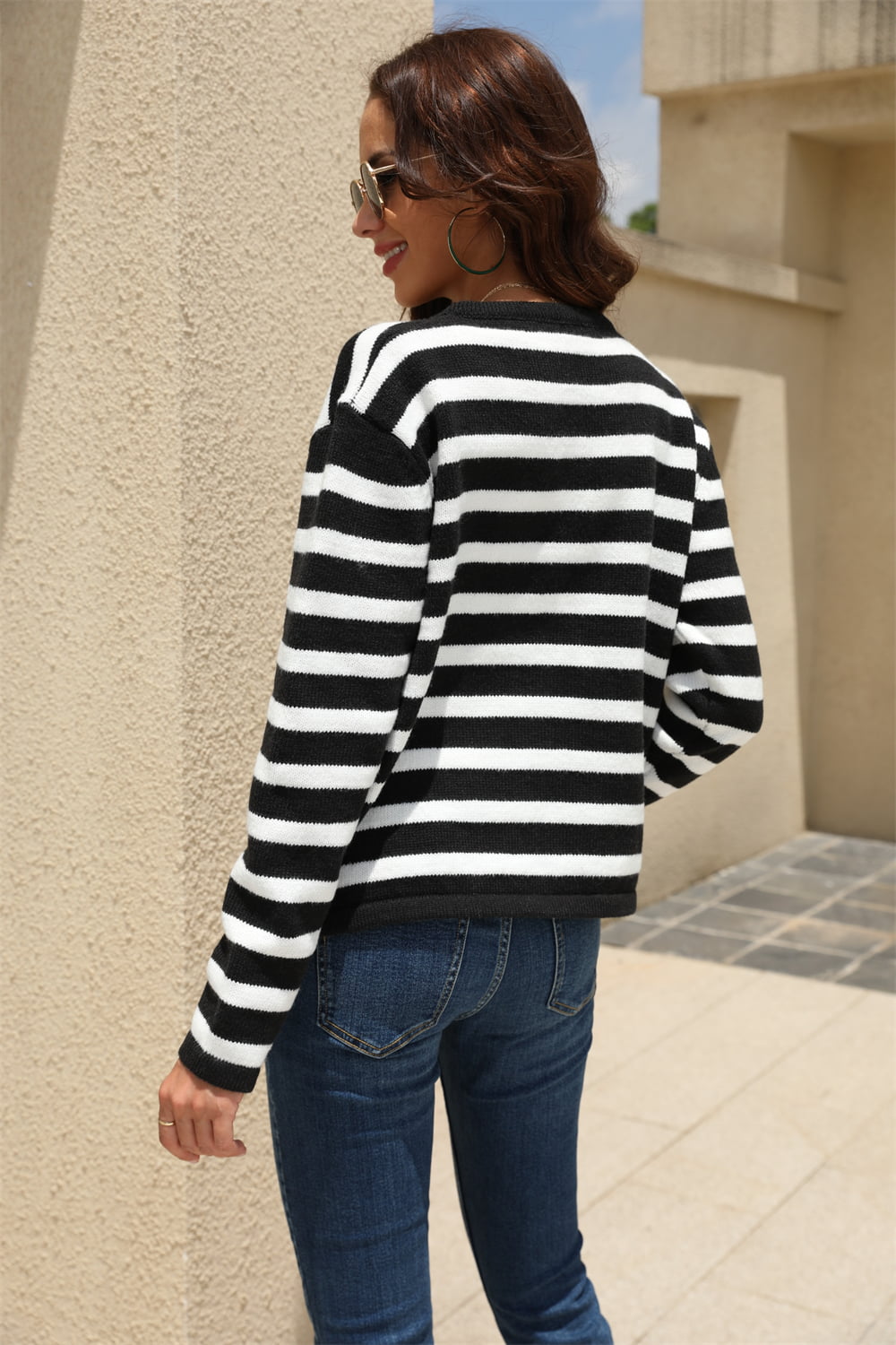 Black and white striped crewneck cardigan with button front, styled with jeans.