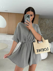Dark gray twist-detail V-neck romper with cinched waist and dolman sleeves.