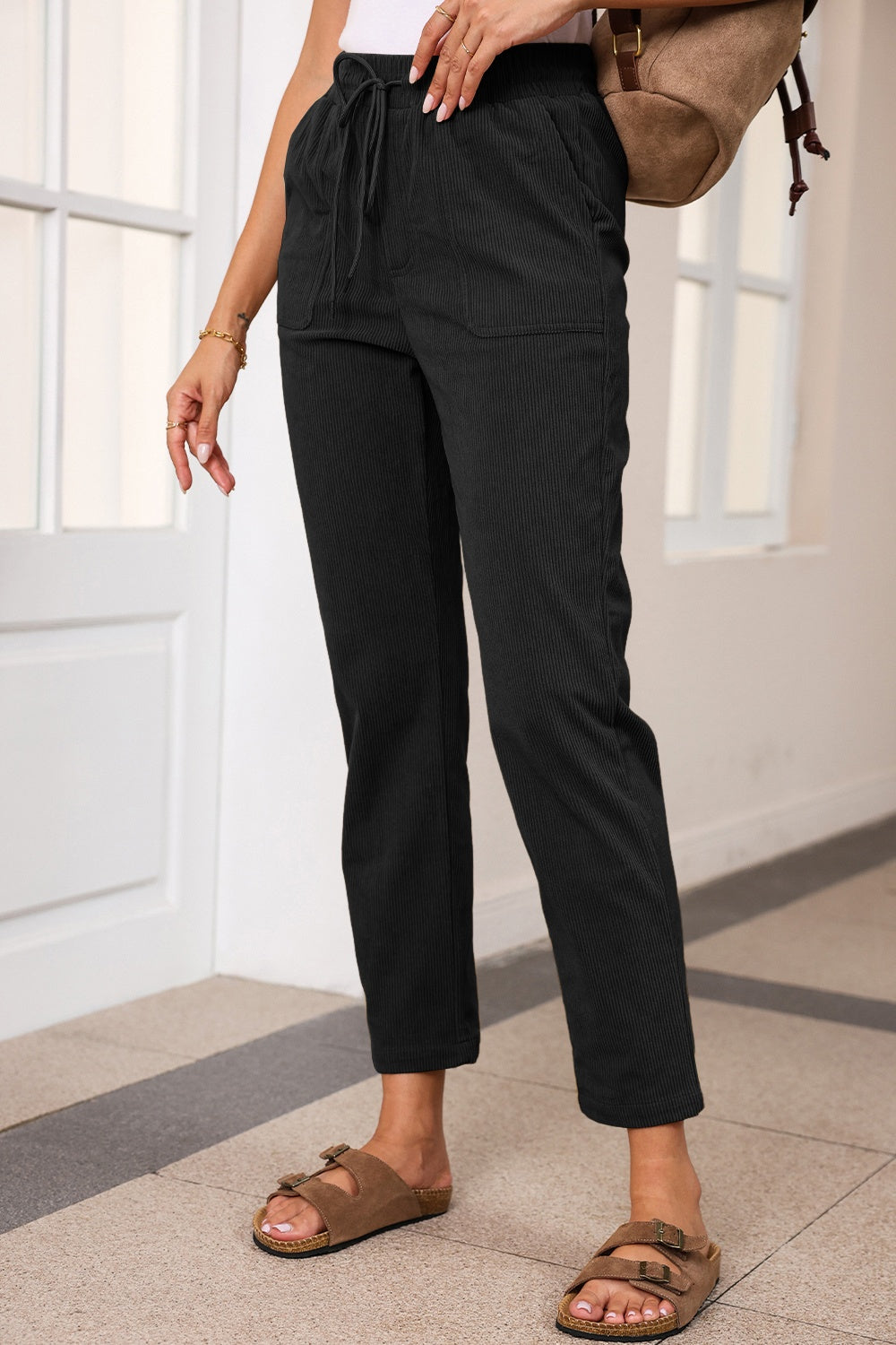 Black corduroy drawstring trousers with slant pockets and a relaxed fit.