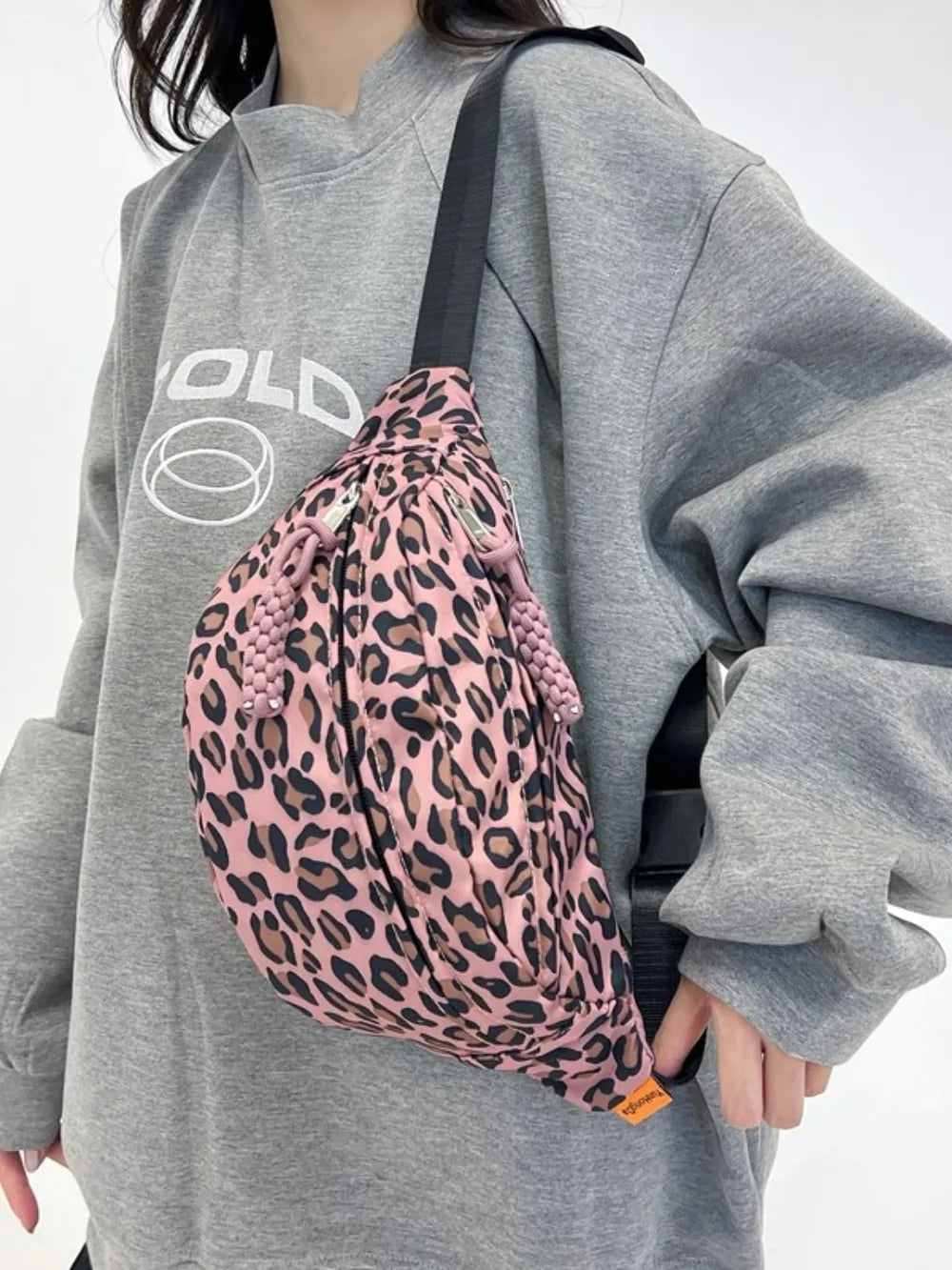 Pleated leopard print sling bag in dusty pink with beaded drawstring details and silver zippers.
