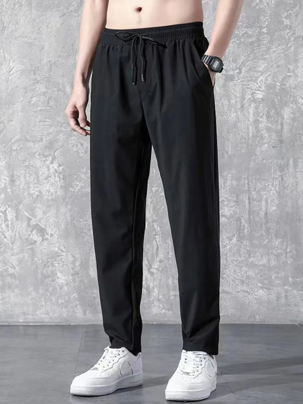 Black relaxed-fit drawstring trousers with elastic waistband and side pockets.