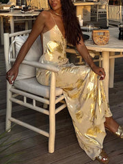Cream backless V-neck maxi gown with abstract gold foil pattern.