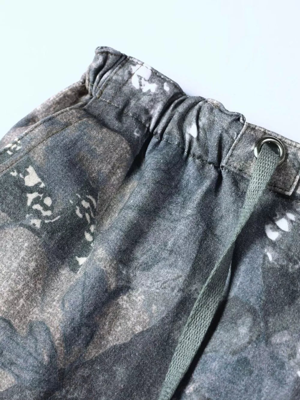 Men's camouflage cargo sweatpants with drawstring waist and metal eyelet detail.
