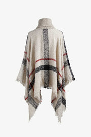 Beige plaid turtleneck cape with fringe detail and textured acrylic knit.