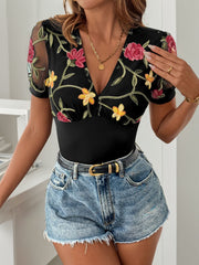Black mesh sleeve bodysuit with floral embroidery and deep V-neck.
