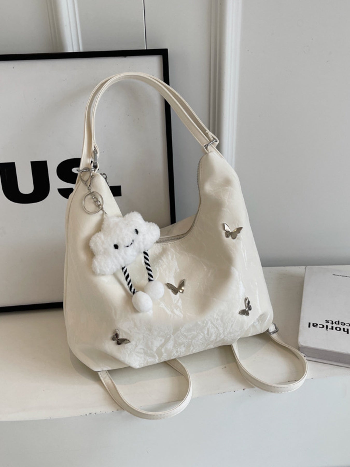 White shoulder bag with butterfly appliques and a cloud charm.