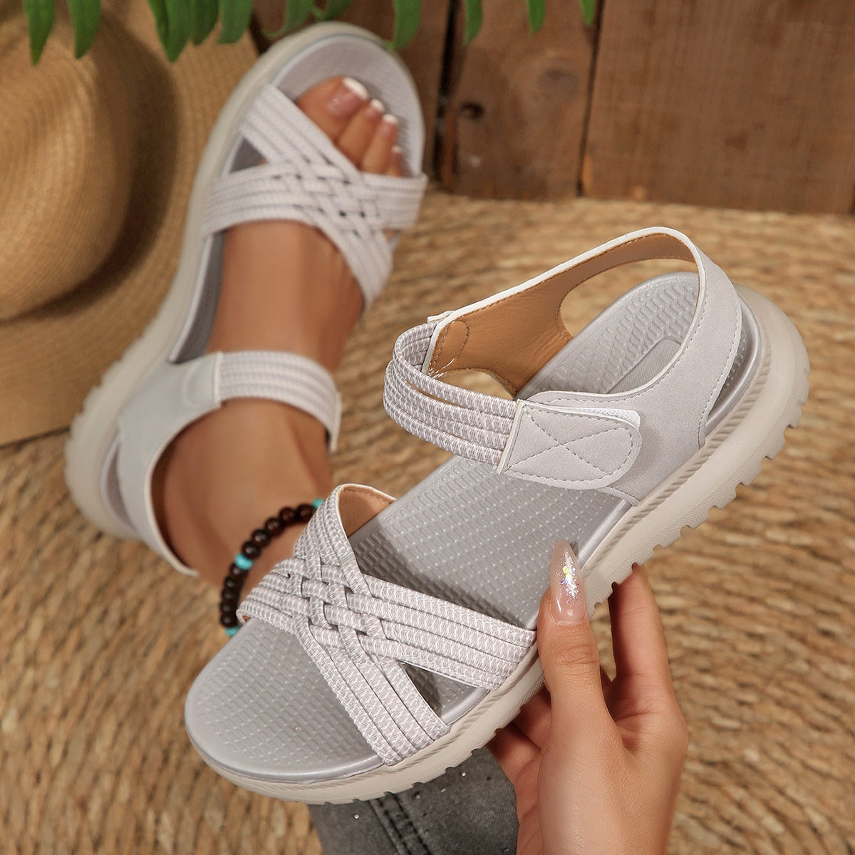 Gray woven strap open-toe flat sandals with adjustable ankle strap and cushioned sole.