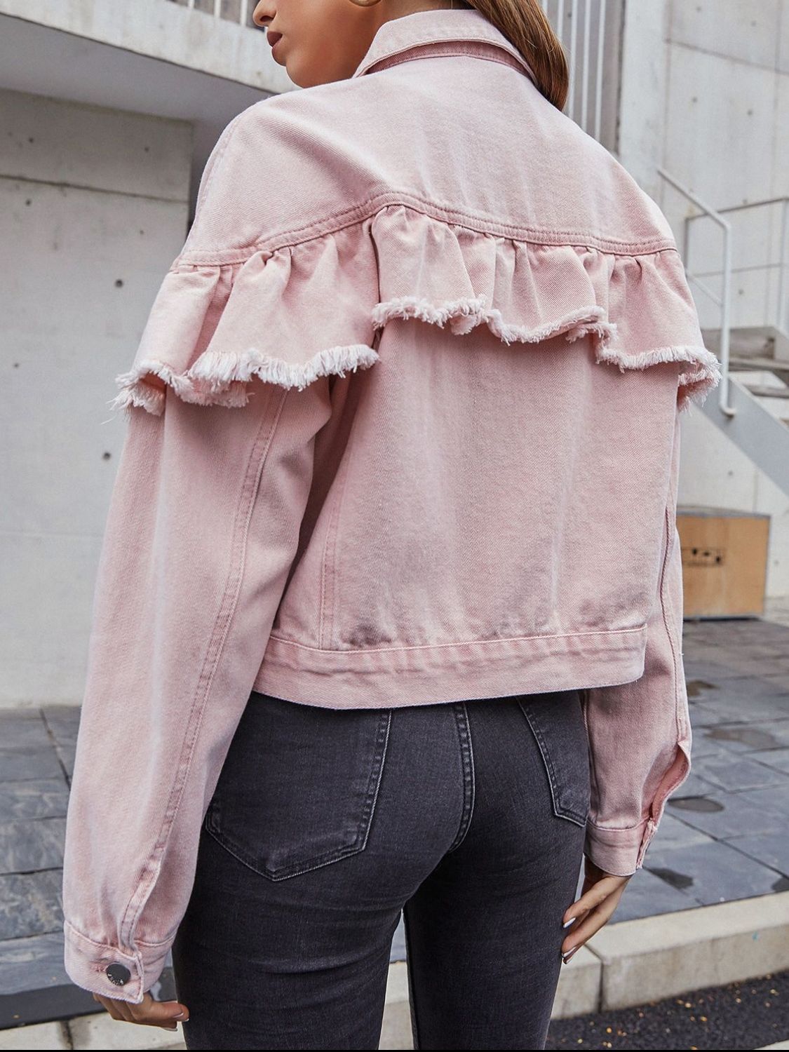 Blush pink denim trucker jacket with frayed ruffle detail across the back yoke.