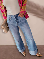 Distressed high-waisted flare maternity jeans with raw hem detail and cuffed legs.