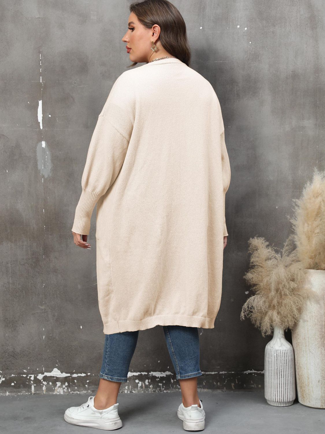 Cream oversized knit duster cardigan with patch pockets and ribbed cuffs.