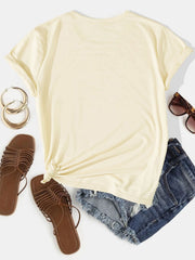 Light yellow t-shirt with rolled sleeves and knotted hem, styled with denim shorts and sandals.